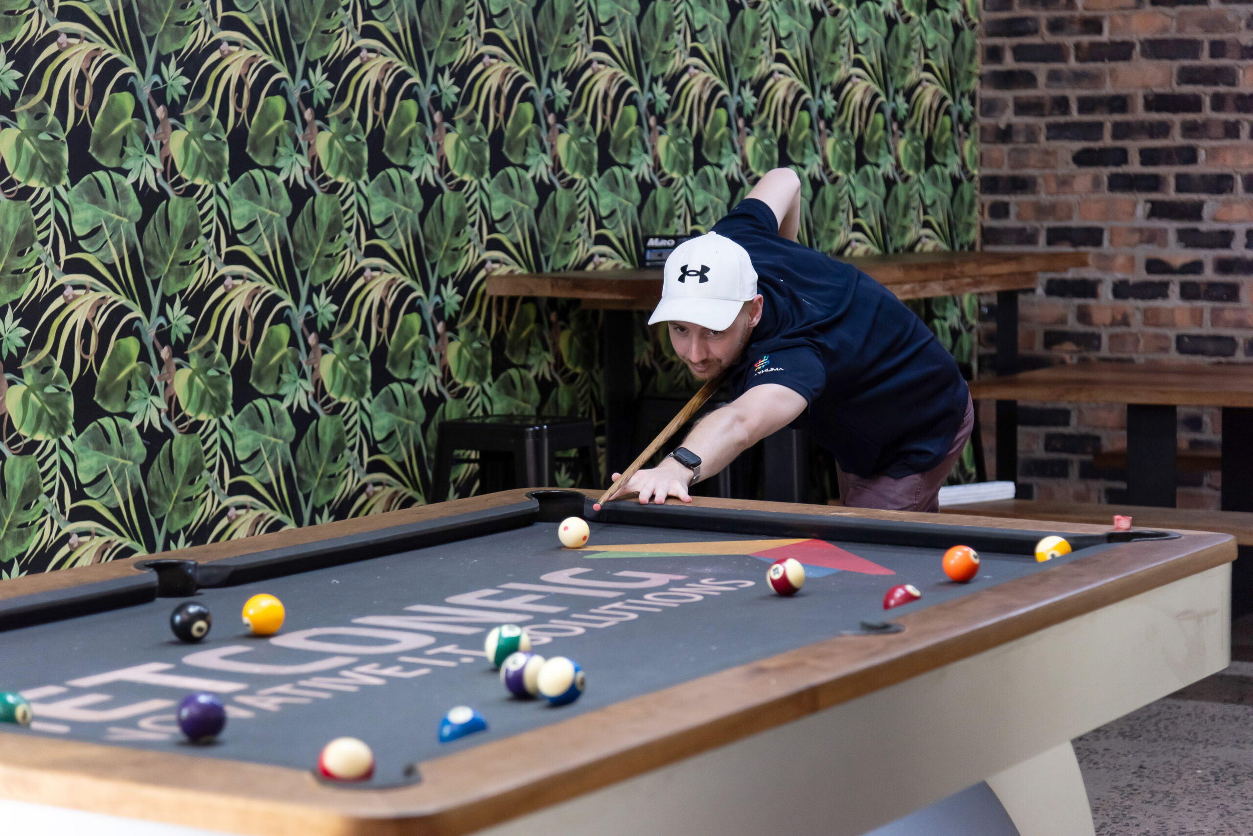 A NETCONFIG team member lining up a shot at the office pool table